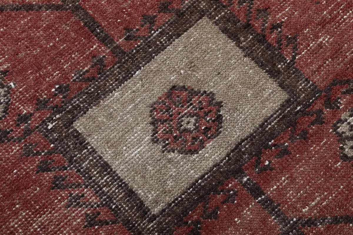 Close-up of a central square motif with a floral-like design in beige and rust tones