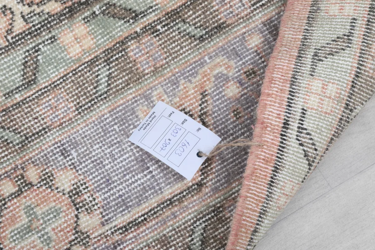 Close-up of the rug's back with a product tag, displaying the tight hand-knotted construction.