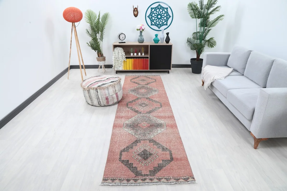 Vintage rose and charcoal runner rug displayed in a living room hallway setting with light flooring.
