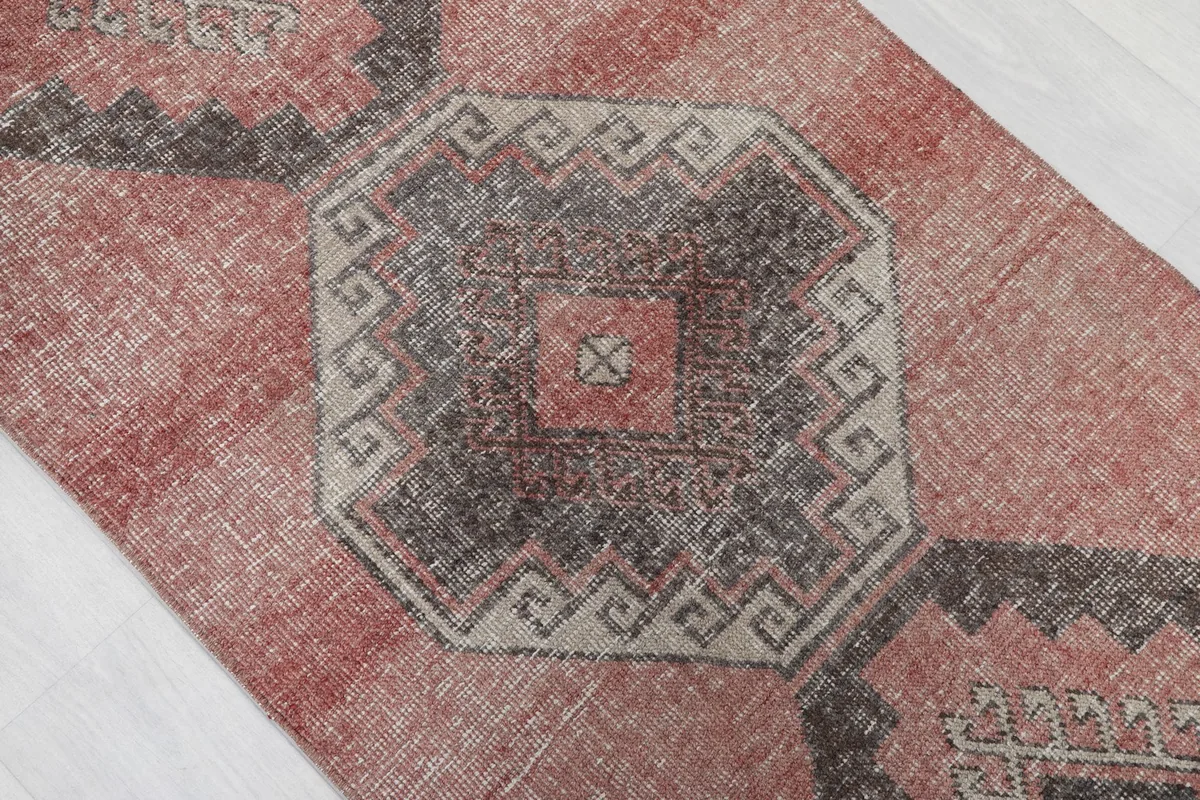Close-up of a central charcoal and beige geometric medallion pattern on the vintage runner.