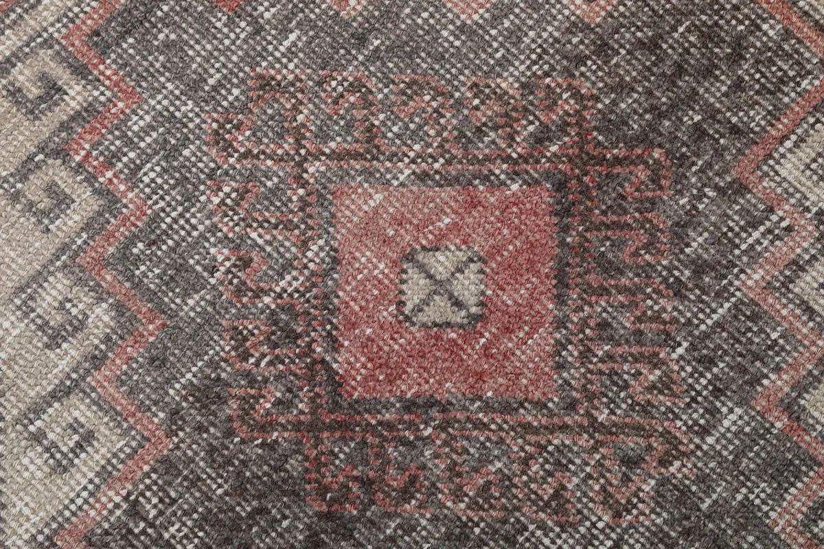 Extreme close-up showing the intricate knotting and faded colors within a charcoal motif.