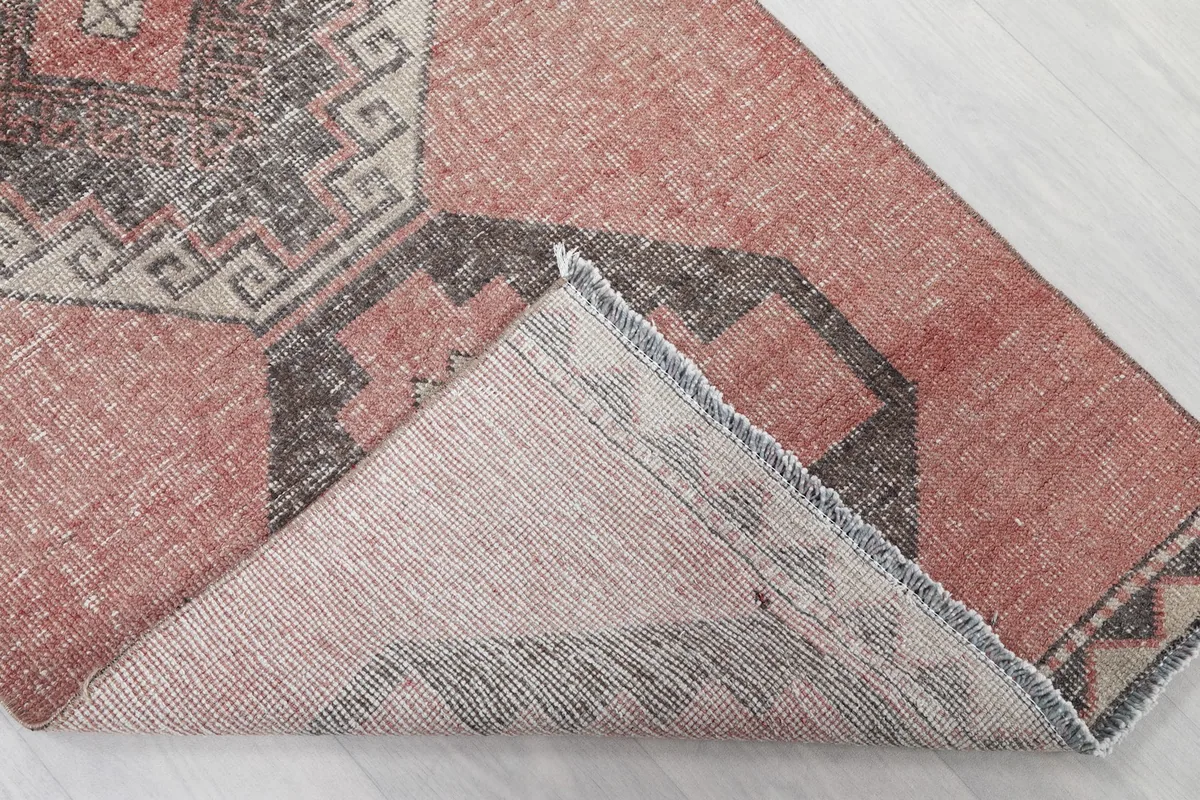 Backside view of a folded corner of the hand-knotted wool rug, showing the cotton foundation.