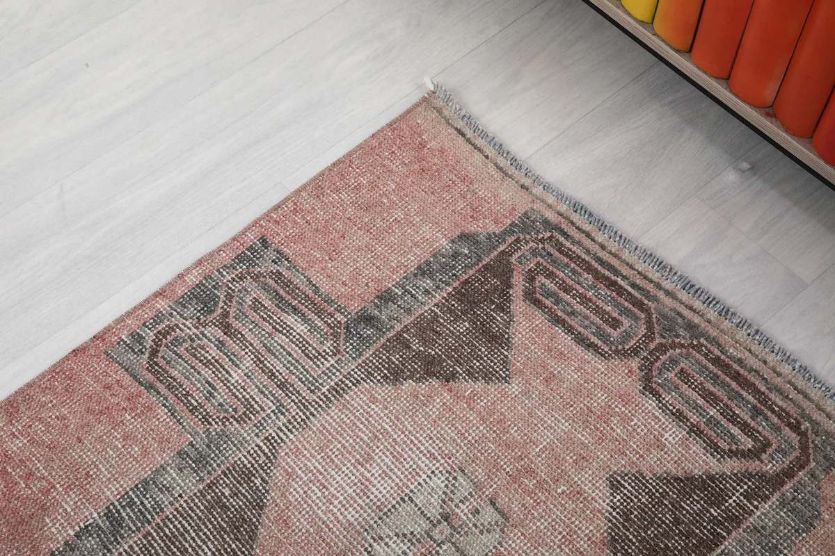 Corner detail of the runner, showing the edge finish and the faded rose and gray tones.