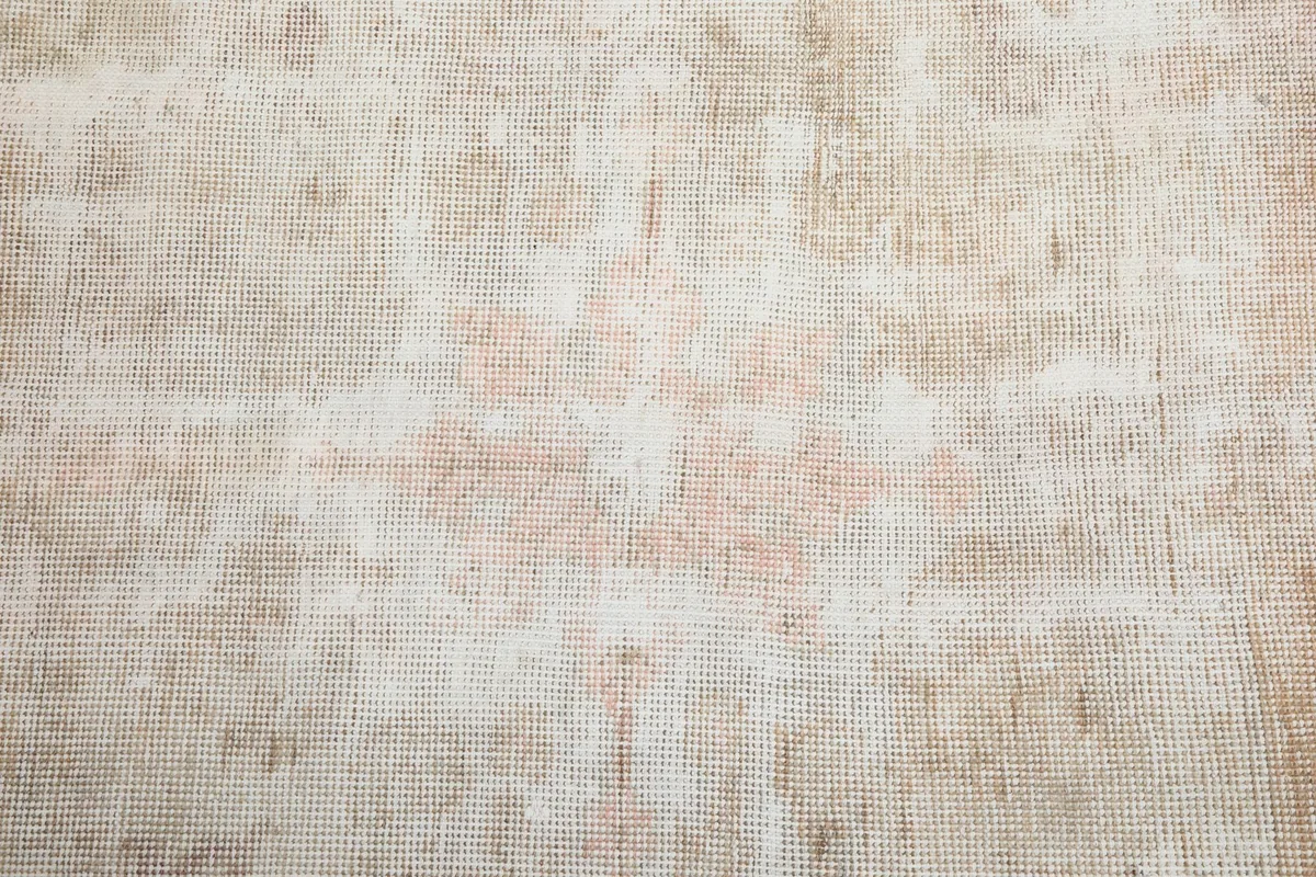 Close-up of the rug's central field, showing the worn wool pile and subtle patterns