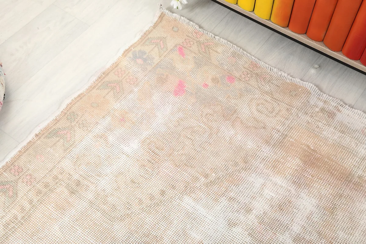Corner detail of the rug, showing the blend of beige, rose, and gray tones