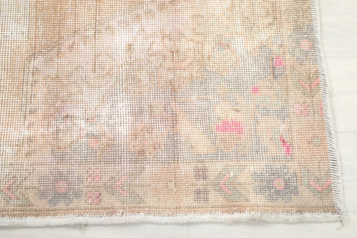 Detail of the rug's border with faded rose and gray geometric patterns