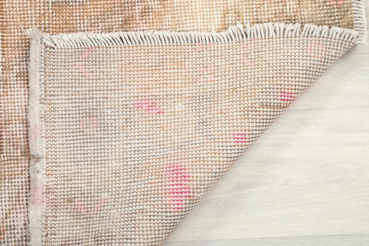 Underside view of the rug, revealing the tightly woven cotton foundation and short fringes