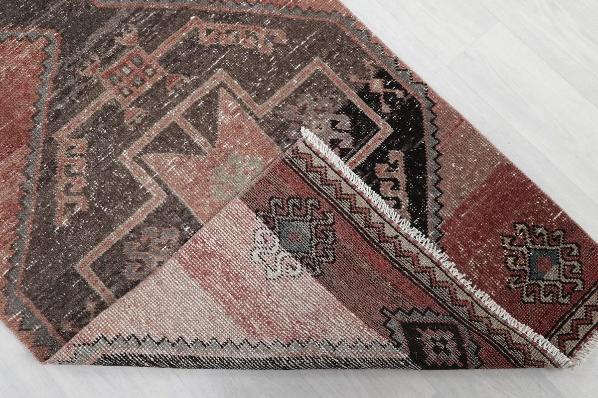 Corner of the rug folded back, revealing the hand-knotted construction and cotton foundation