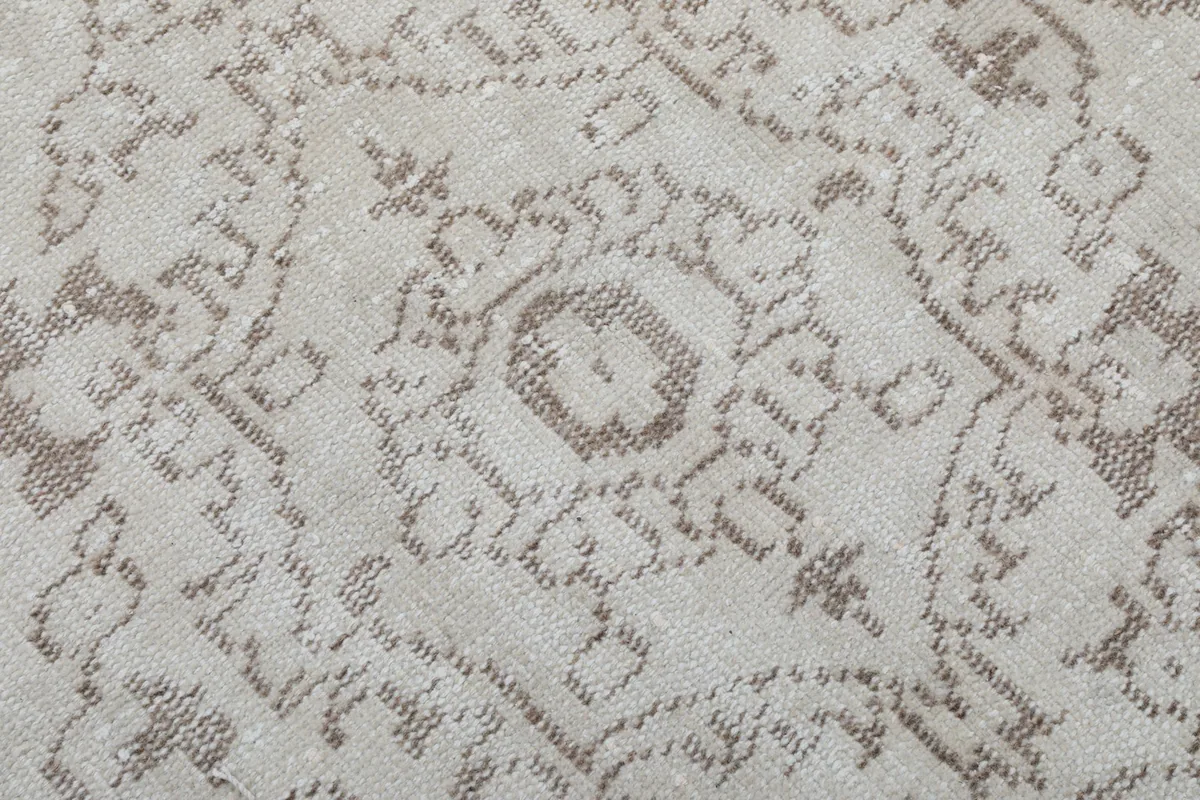 Close-up texture of the low wool pile, showing the hand-knotted detail and faded gray motifs