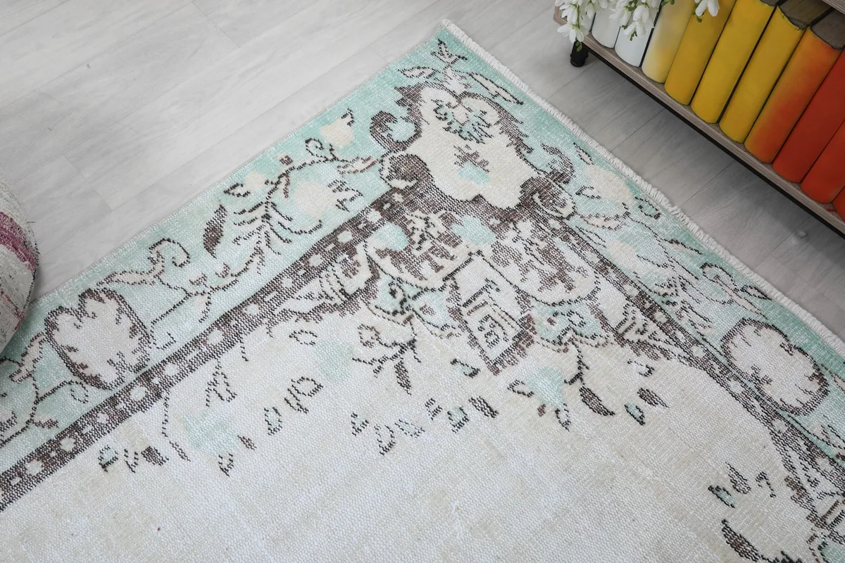Close-up of the rug's border and corner design with faded green and brown hues