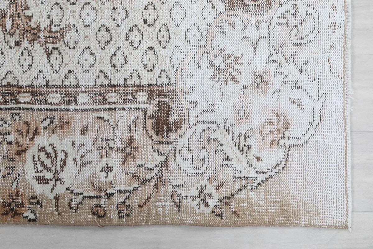 Detailed corner view of the rug's border and field, showcasing the geometric and floral patterns and patina.