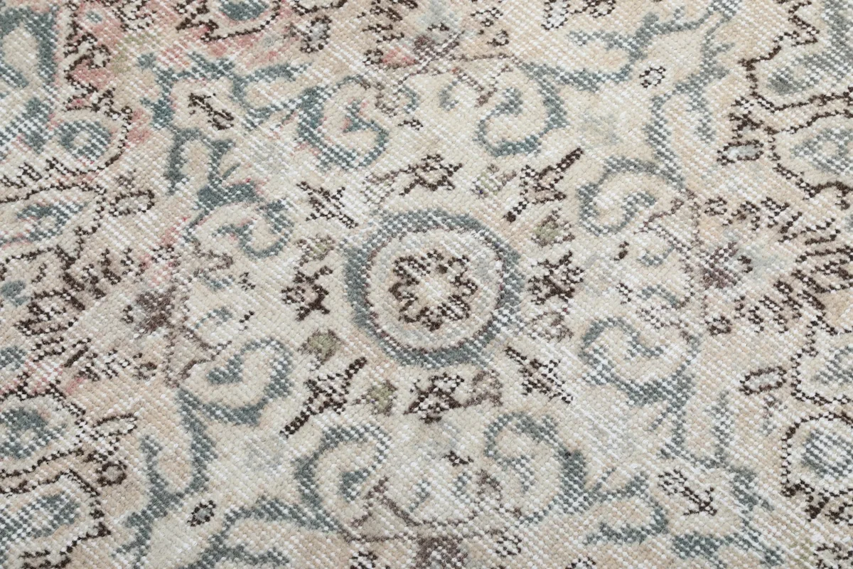 Close-up of the rug's low pile and the subtle variations in its faded blue and beige colors.