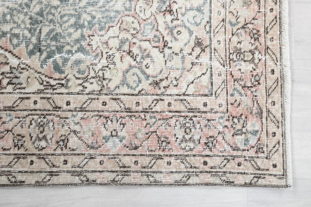 Detailed shot of the rug's intricate rose and beige border pattern.