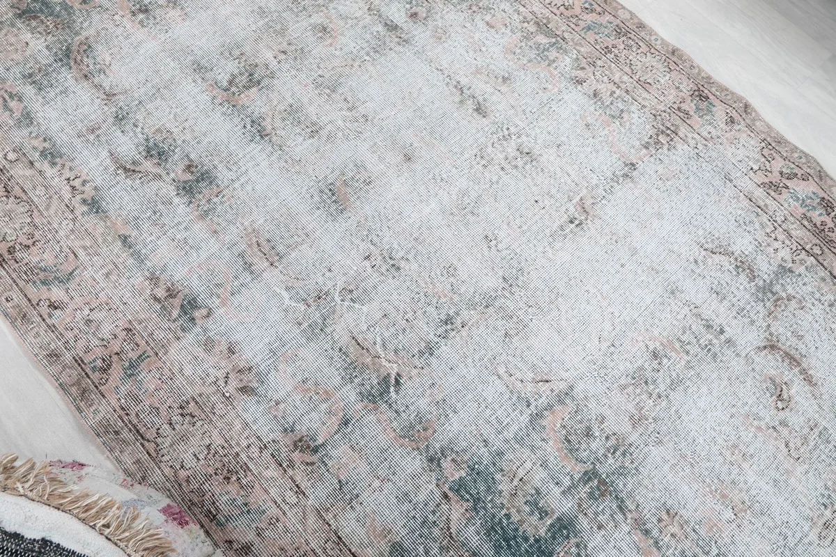 Angled shot showcasing the overall distressed character and subtle color variations of the rug's field.