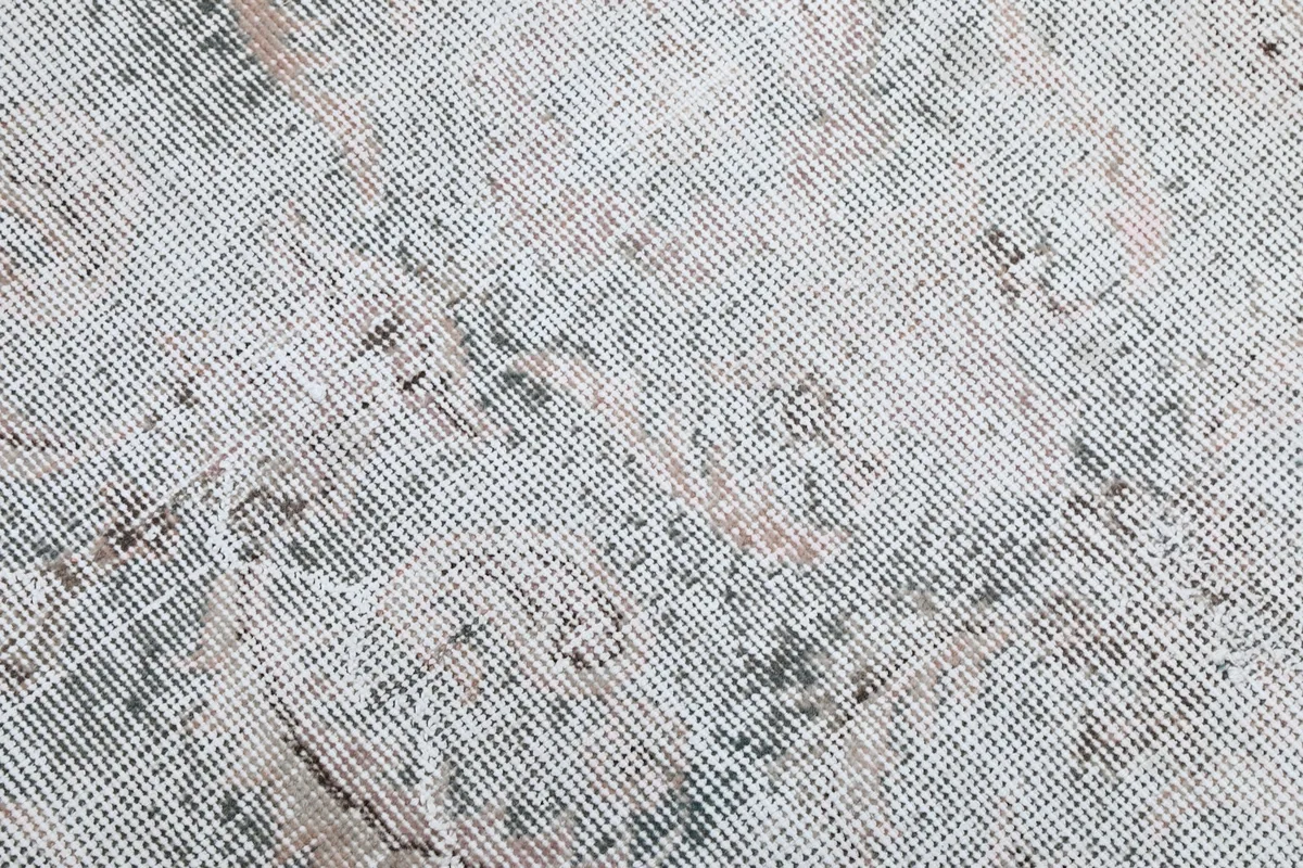 Close-up of the low wool pile, revealing the hand-knotted texture and distressed areas.