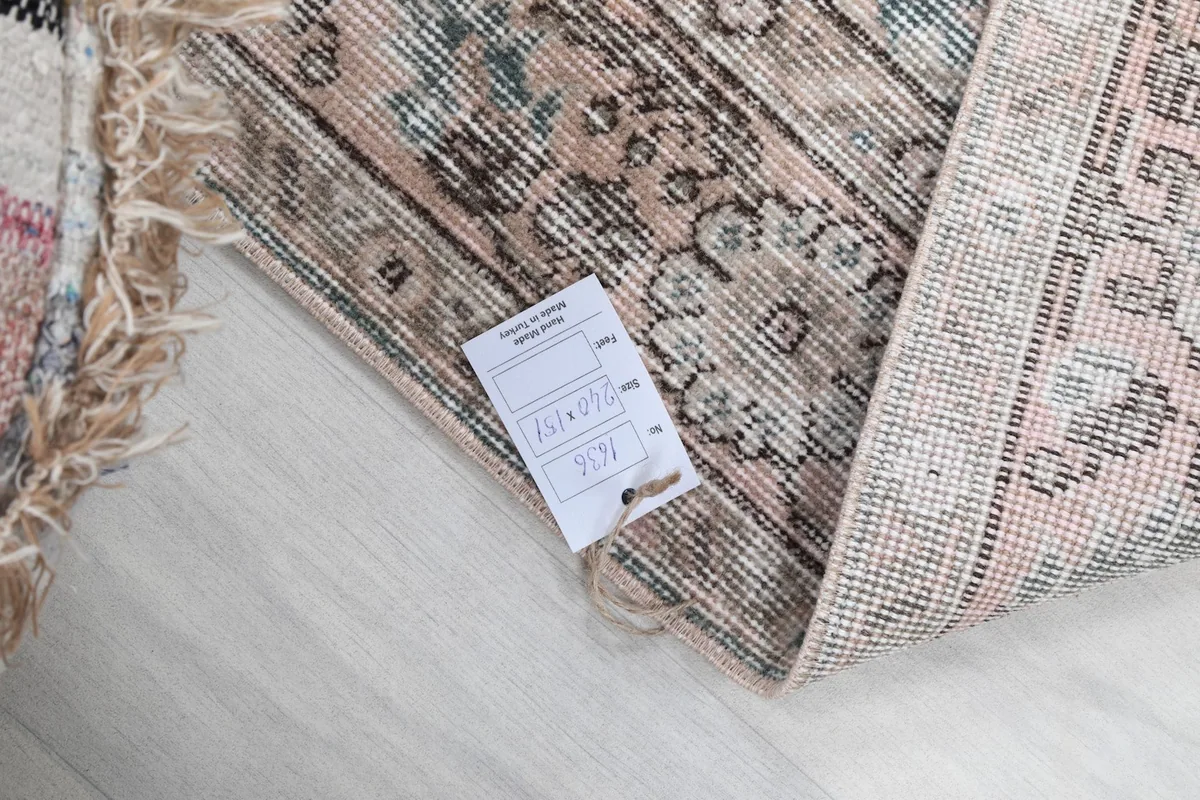 Corner of the rug with a tag, showing the reverse side and the texture of the wool and cotton.