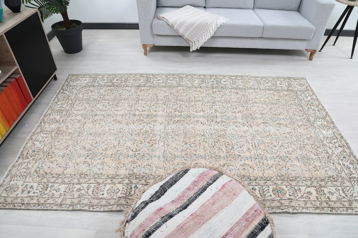 Overhead view of the beige and blue vintage Anatolian rug in a room, with furniture around it