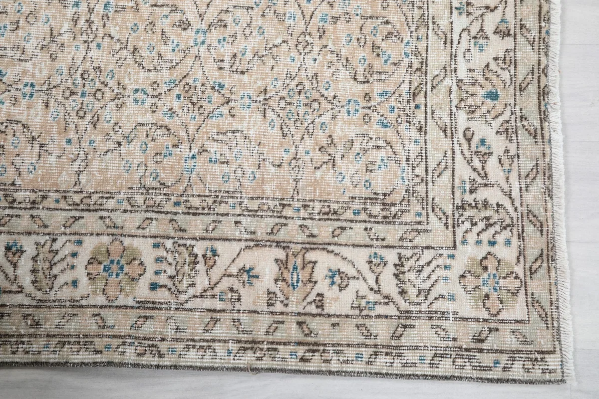 Detail of the border design on the beige and blue vintage Anatolian rug with floral motifs