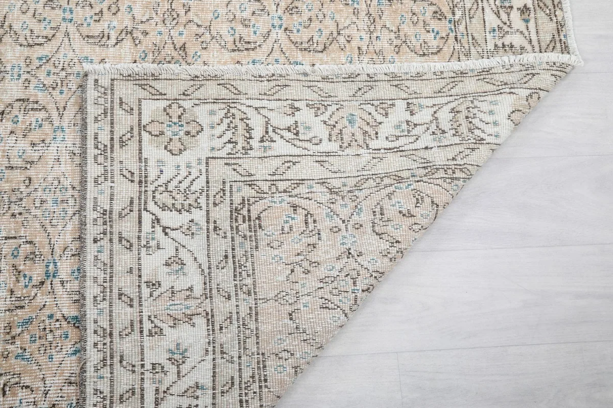 Close-up of the fringe and corner of the beige and blue vintage Anatolian rug, revealing construction