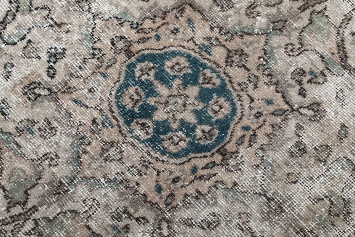 Very close detail of the central motif within the medallion, showing blue and beige threads