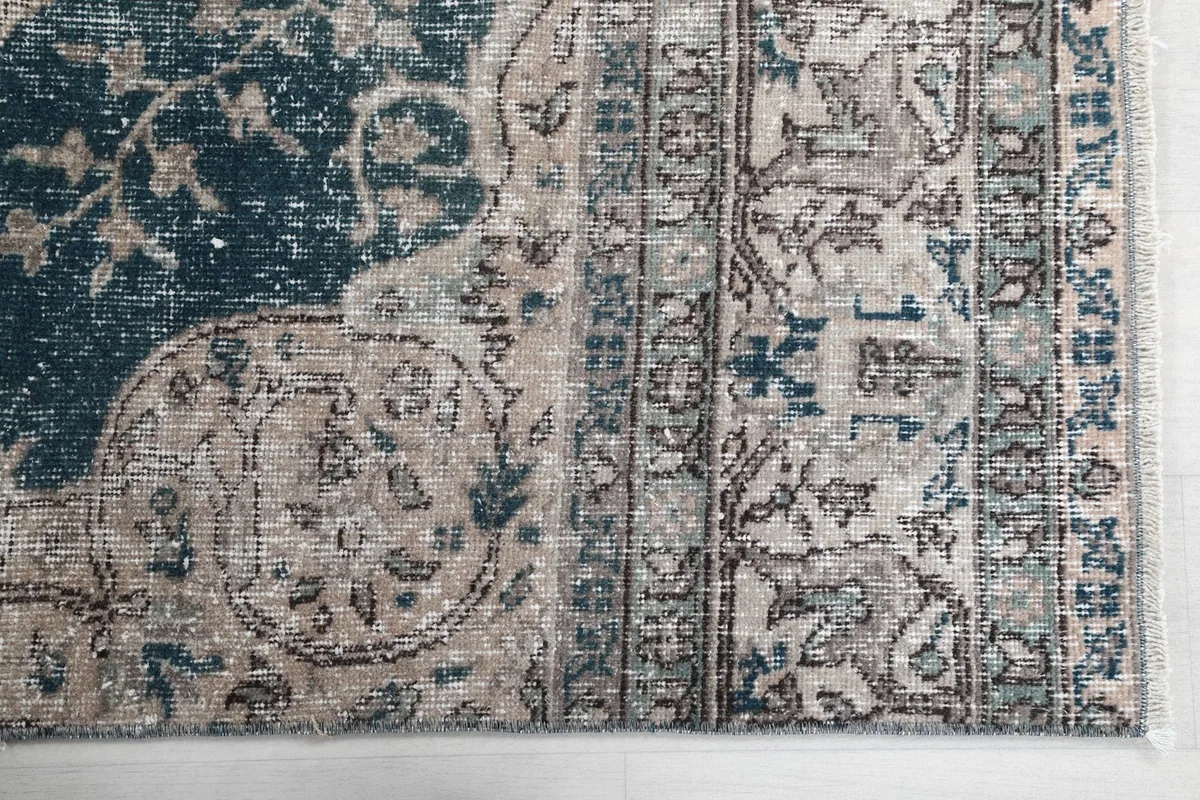 Detailed view of the rug's border design and corner, highlighting blue and beige motifs