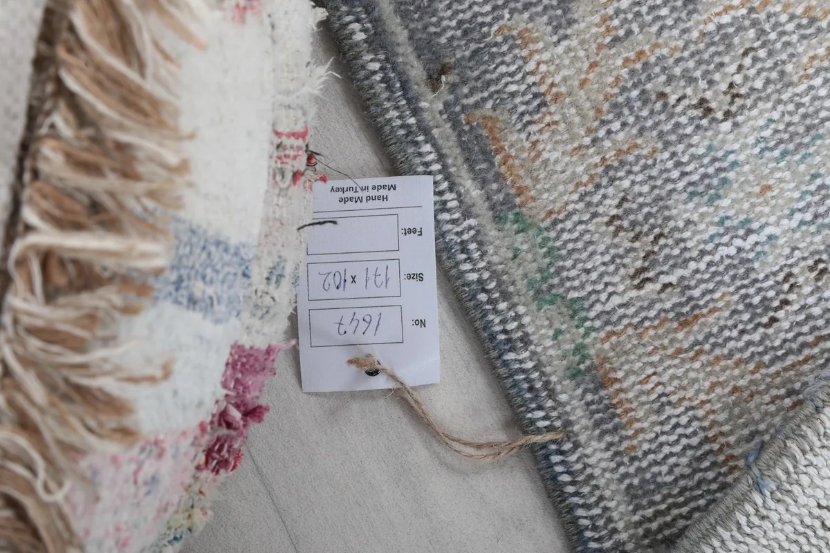 Product tag showing dimensions and origin, next to the rug's fringe