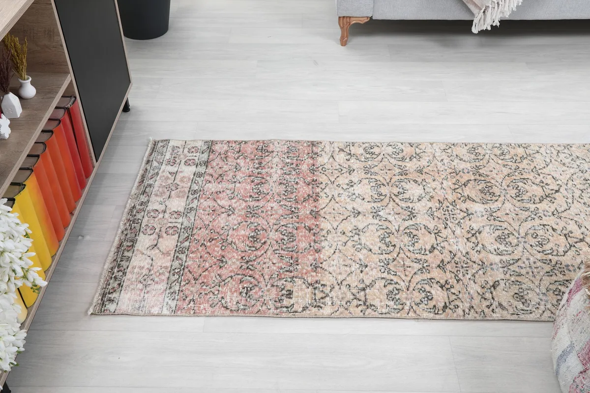 Angled full view of the runner rug in a room, emphasizing its long, narrow shape and color blend.
