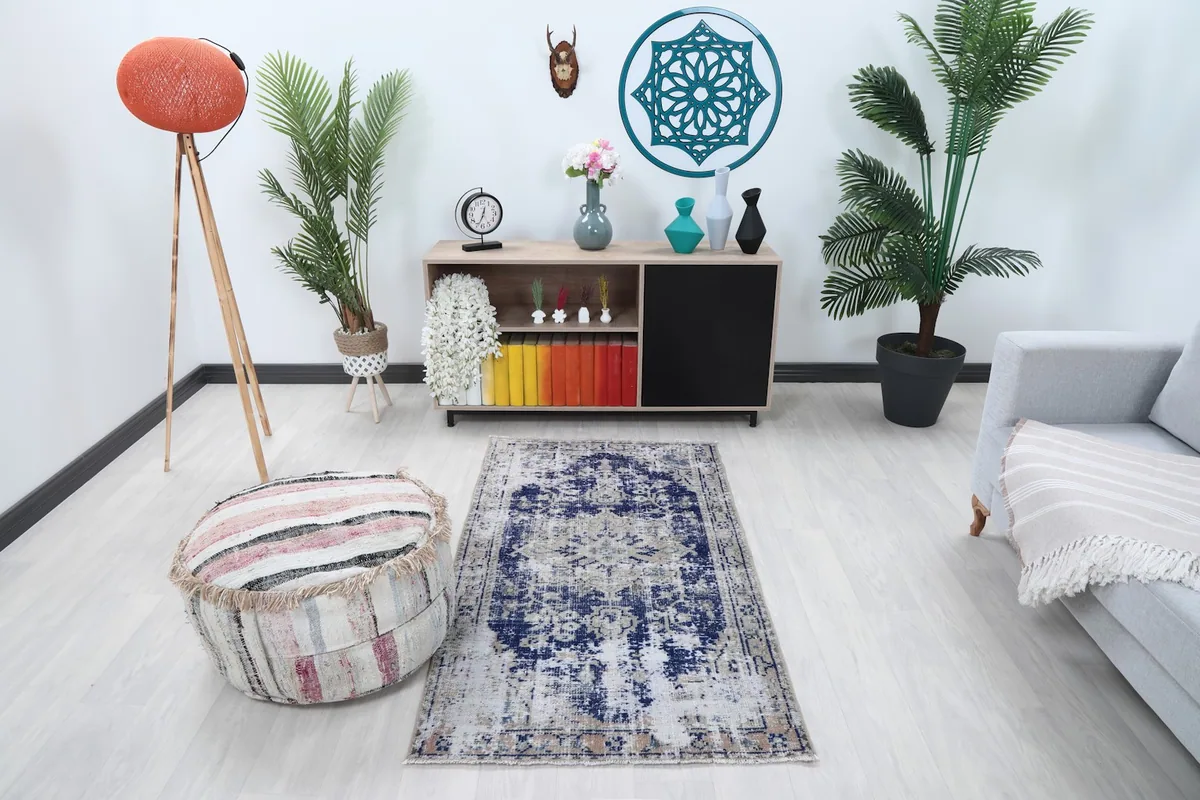 Navy and beige vintage rug placed in a modern living room setting with a light gray couch and wooden furniture.