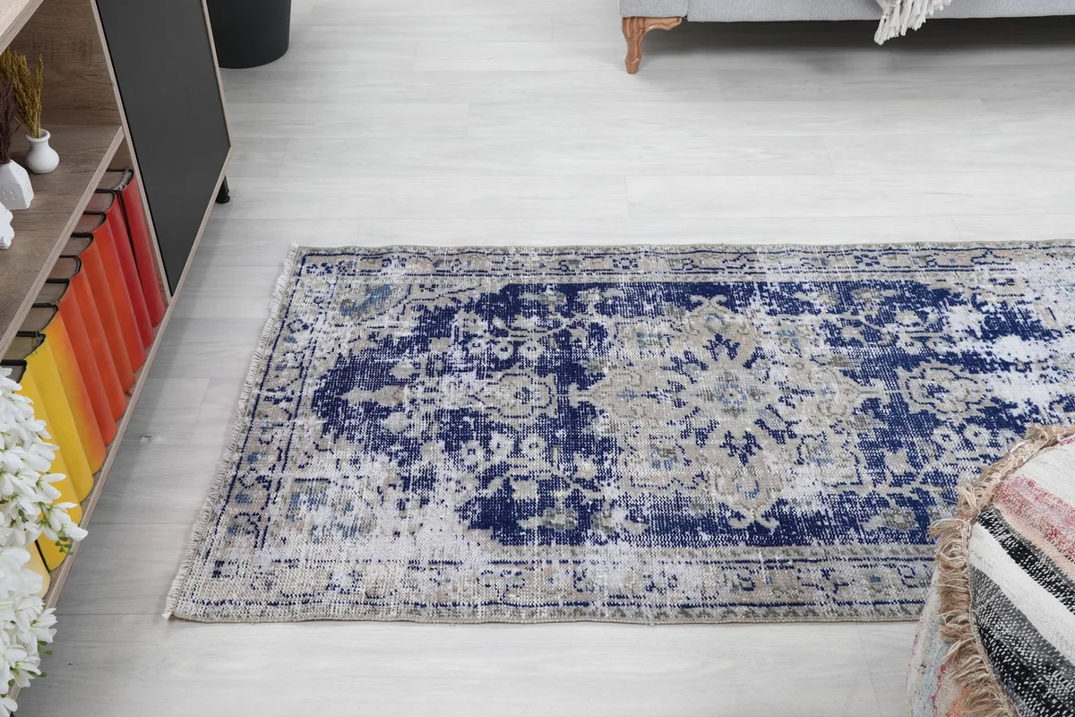 Wider angle view of the rug in the living room, showcasing its rectangular shape and distressed appearance.