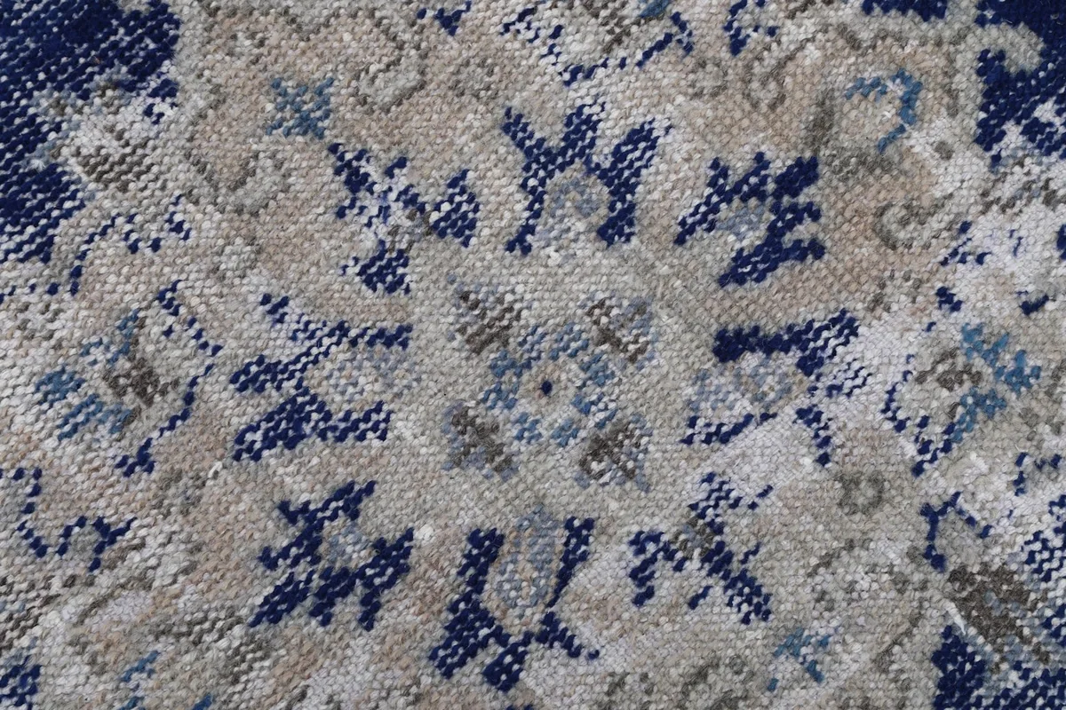 Close-up detail of the hand-knotted wool pile, showing the intricate navy, beige, and gray threads in the pattern.