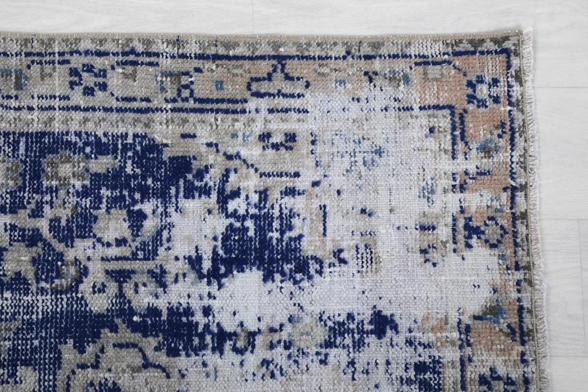 Detail of the upper right corner of the rug, highlighting the distressed border and color variations.