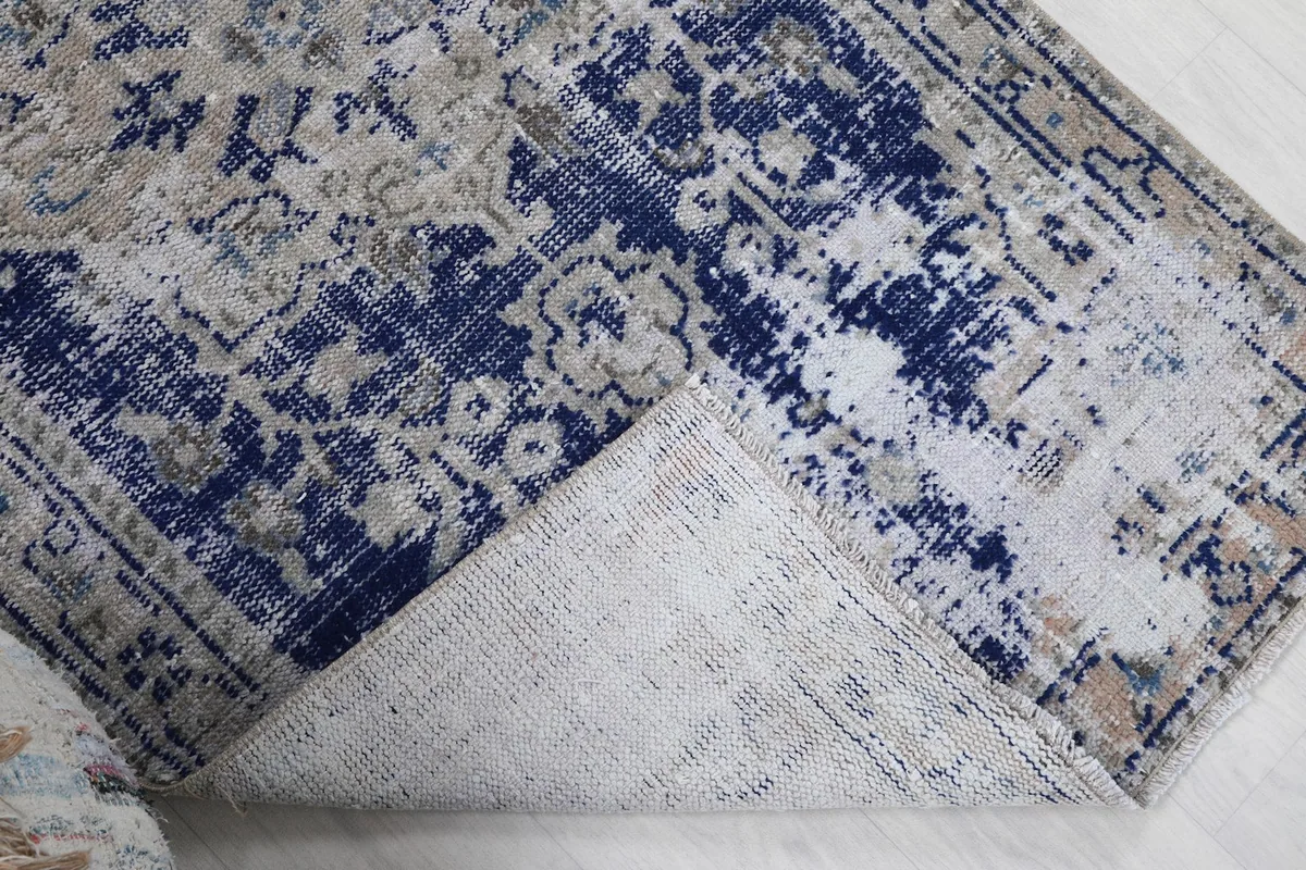 Corner of the rug folded back to reveal the cotton foundation and the reverse side of the hand-knotting.