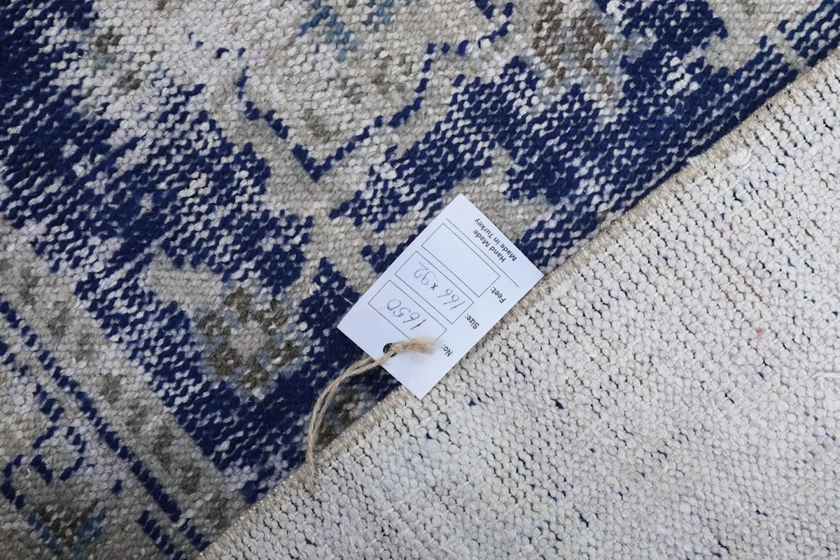Close-up of the rug's back with a product tag, showing the tight hand-knotted weave and cotton foundation.