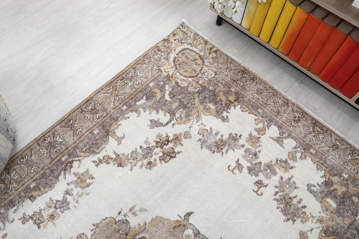 Detail of the rug's outer border and corner, showcasing the faded brown and beige patterns.