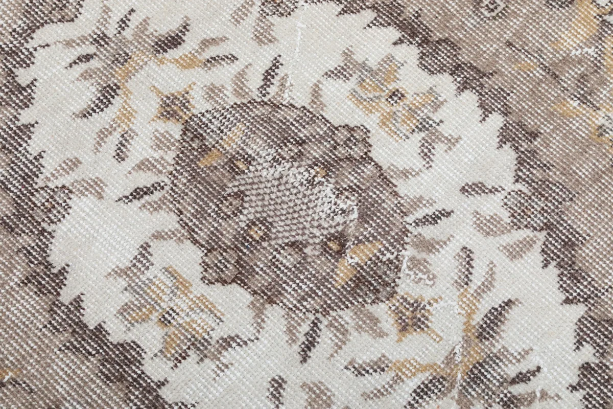 Close-up of the low wool pile, revealing the intricate knotting and color variations within the brown medallion.