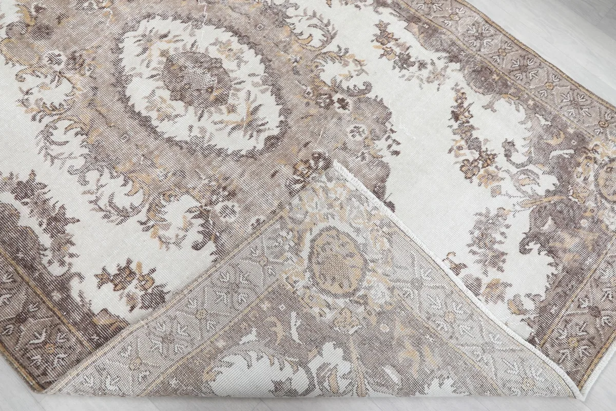View of the rug's reverse side near a corner, showing the cotton foundation and hand-knotted construction.