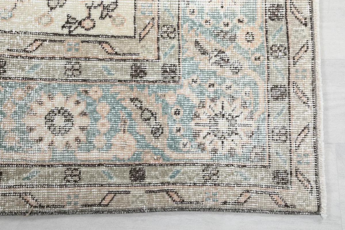 Detailed close-up of the blue and ivory border design and corner motifs of the rug.