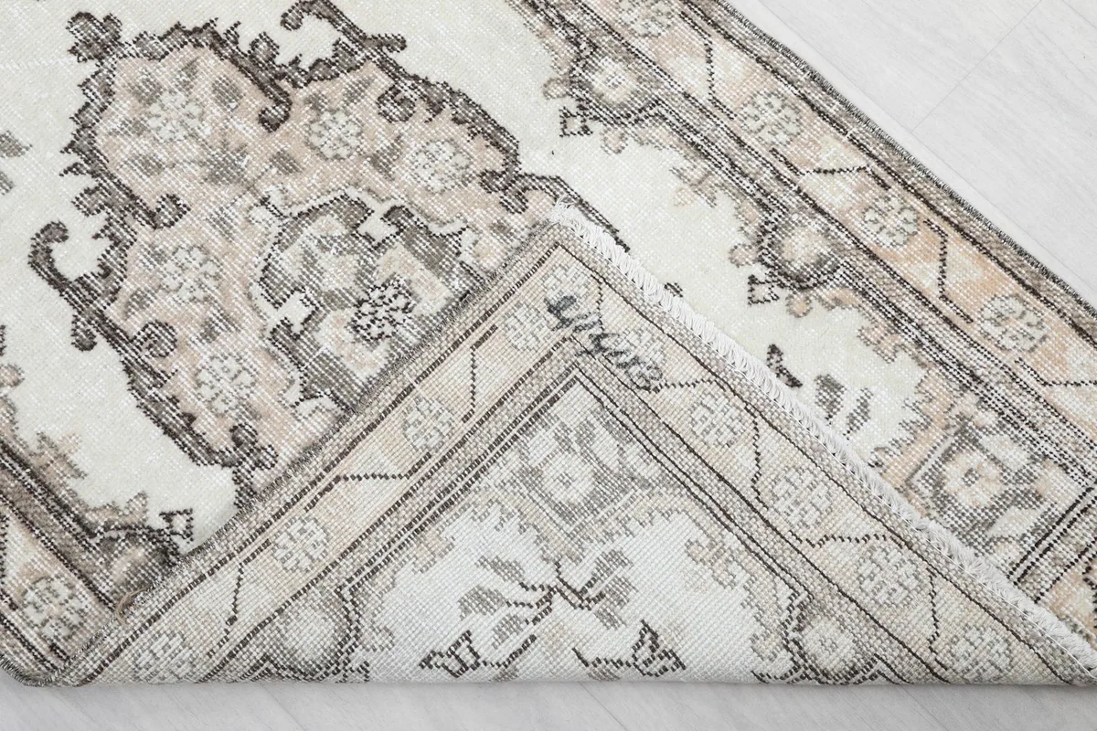 Corner of the rug folded to show the cotton foundation and hand-knotted construction