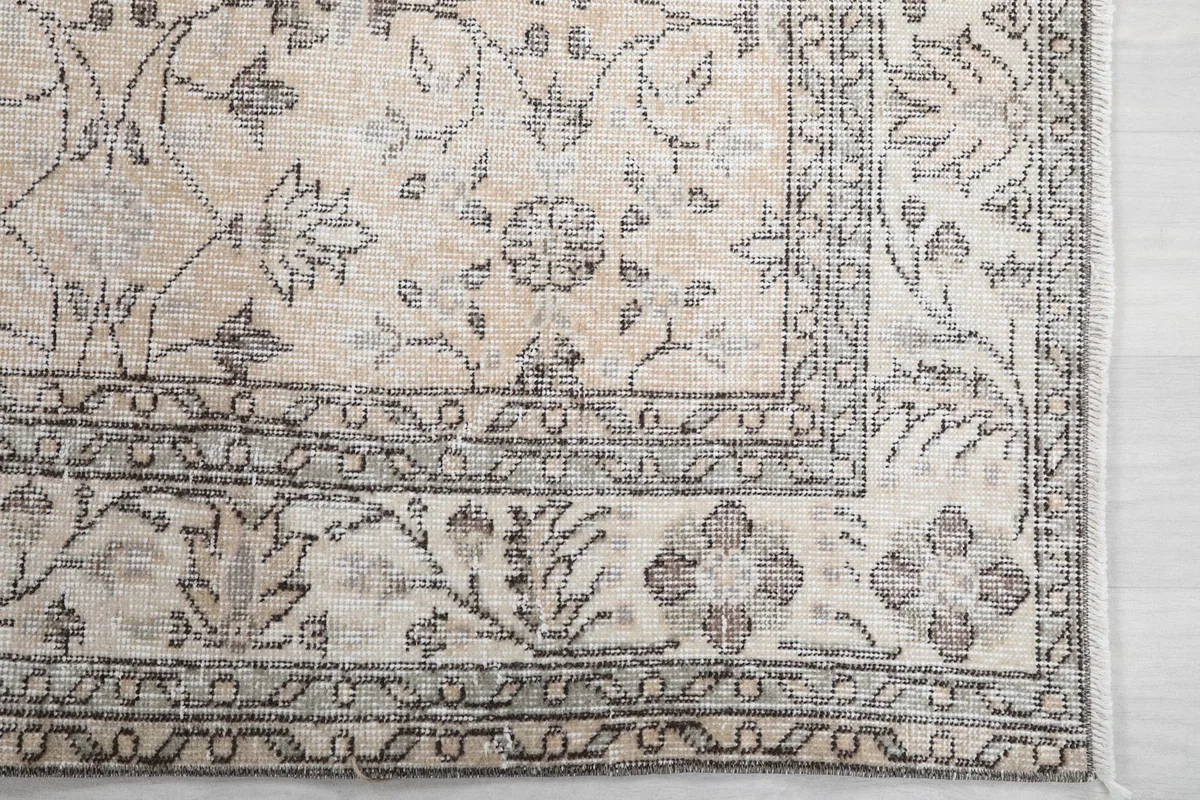 Detailed view of the rug's border and corner, highlighting the intricate gray floral design