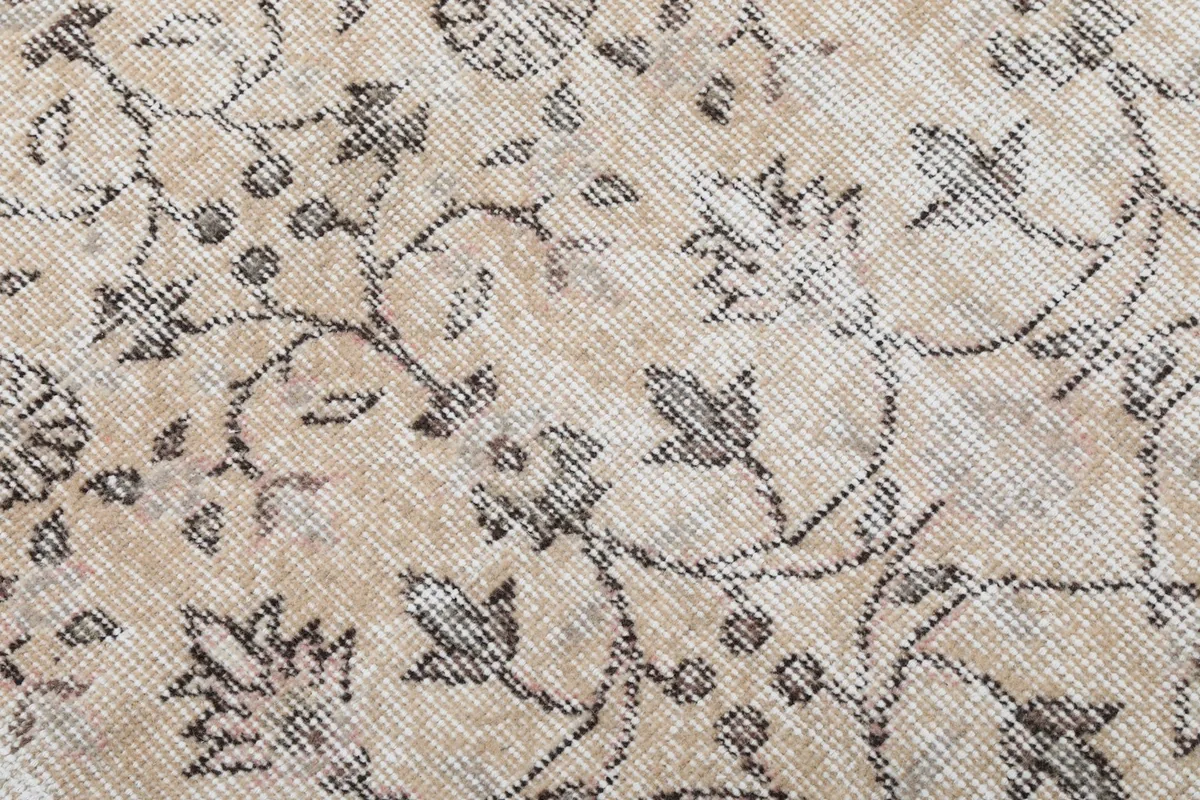 Close-up of the hand-knotted wool pile, showing the detailed gray floral motifs