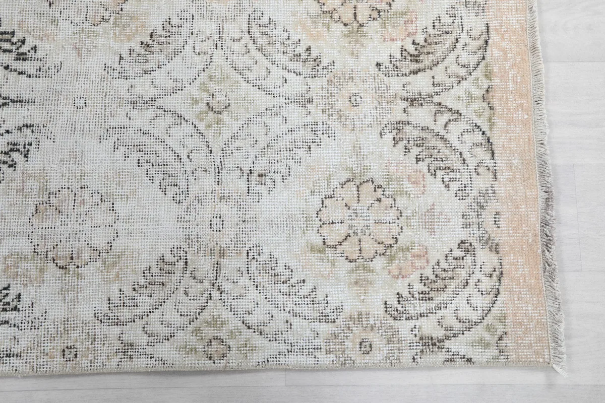 Detailed view of the rug's floral and geometric motifs in ivory, gray, and subtle beige tones