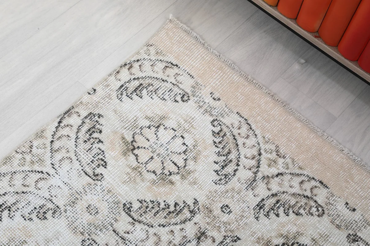 Corner detail of the rug, showing the blend of ivory field and muted gray patterns with slight fringe