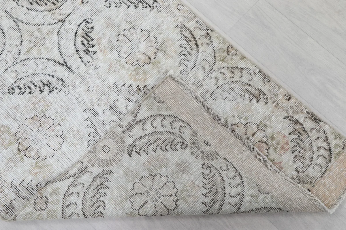 Angled view of the rug with a corner folded back, revealing the wool pile and cotton foundation