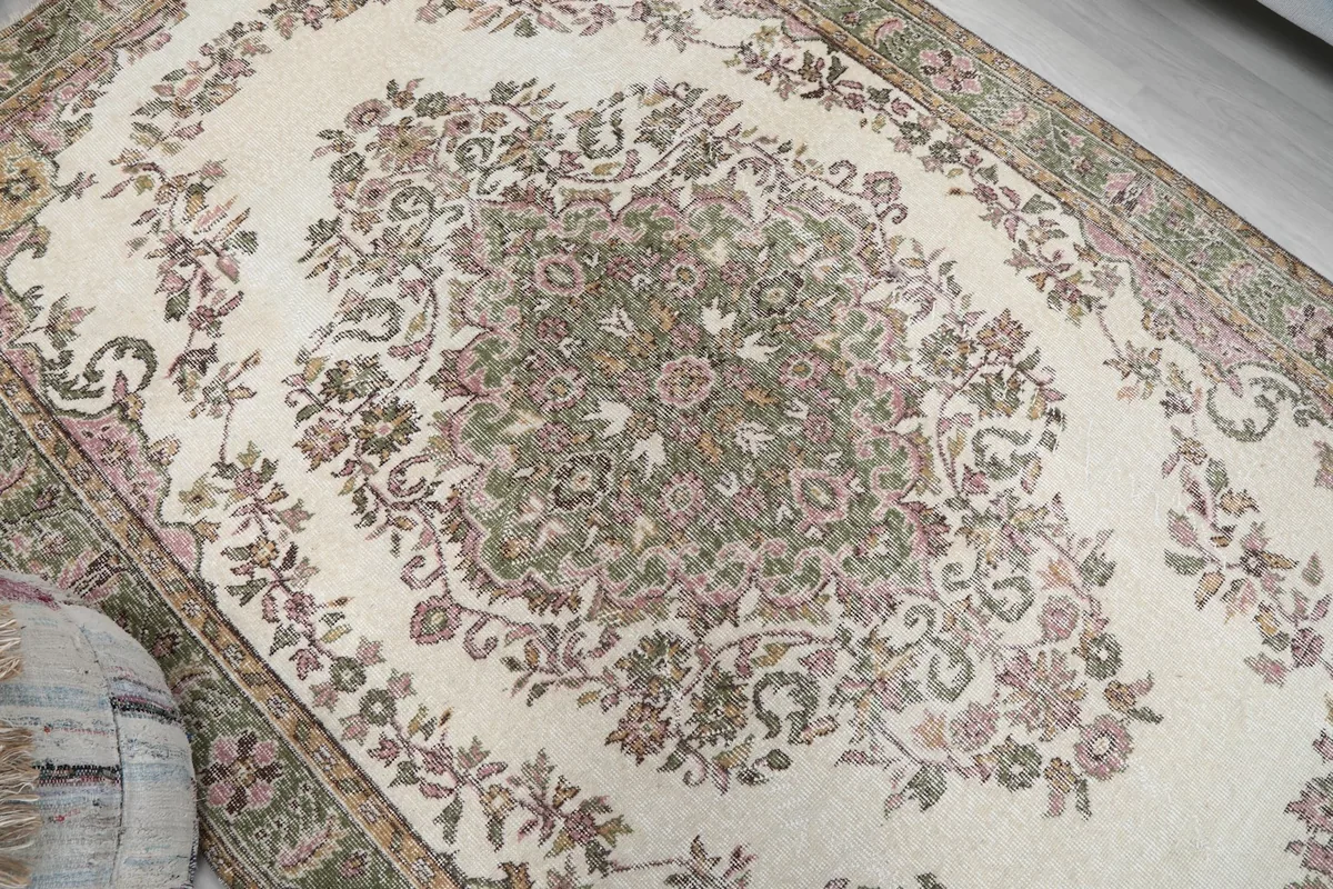 Close-up of the central floral medallion and surrounding motifs on the ivory rug