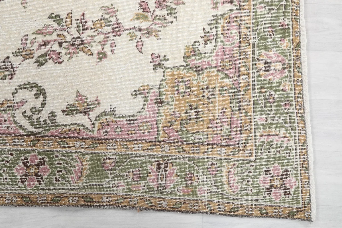 Detail of the green border with pink and gold floral patterns on the vintage rug
