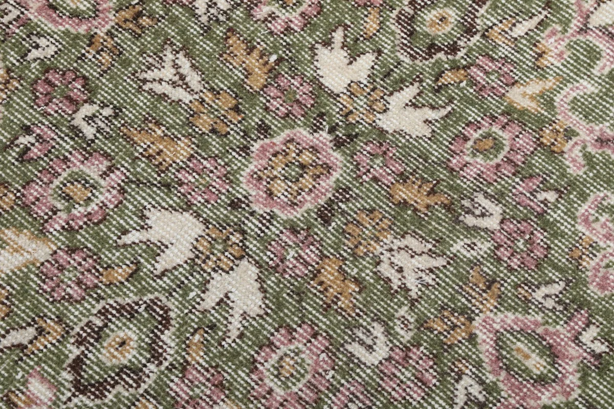 Textured close-up of the low wool pile showing green, pink, and ivory fibers