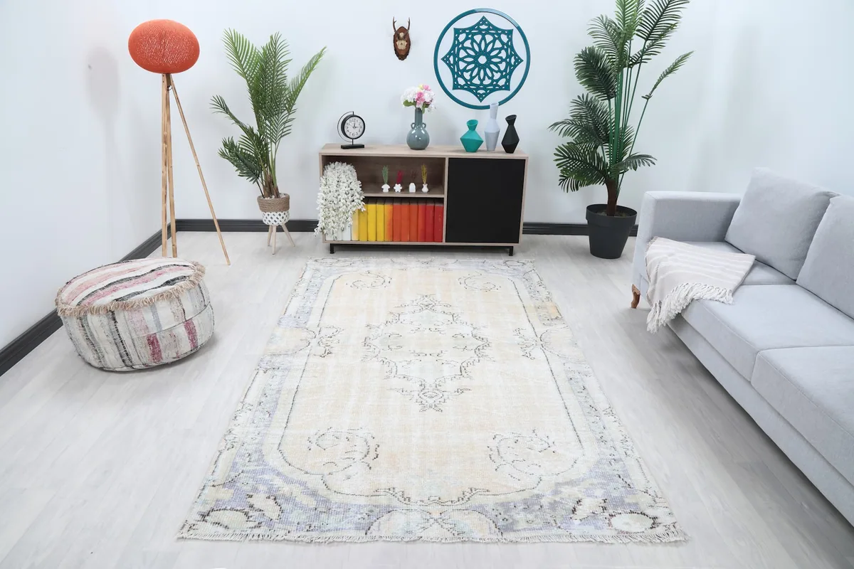 Vintage Anatolian rug with ivory field and gray border in a living room setting with a light gray sofa
