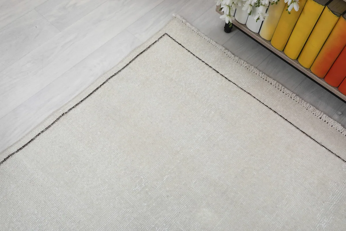 Corner view of the rug, emphasizing the clean lines of the border against the light flooring.