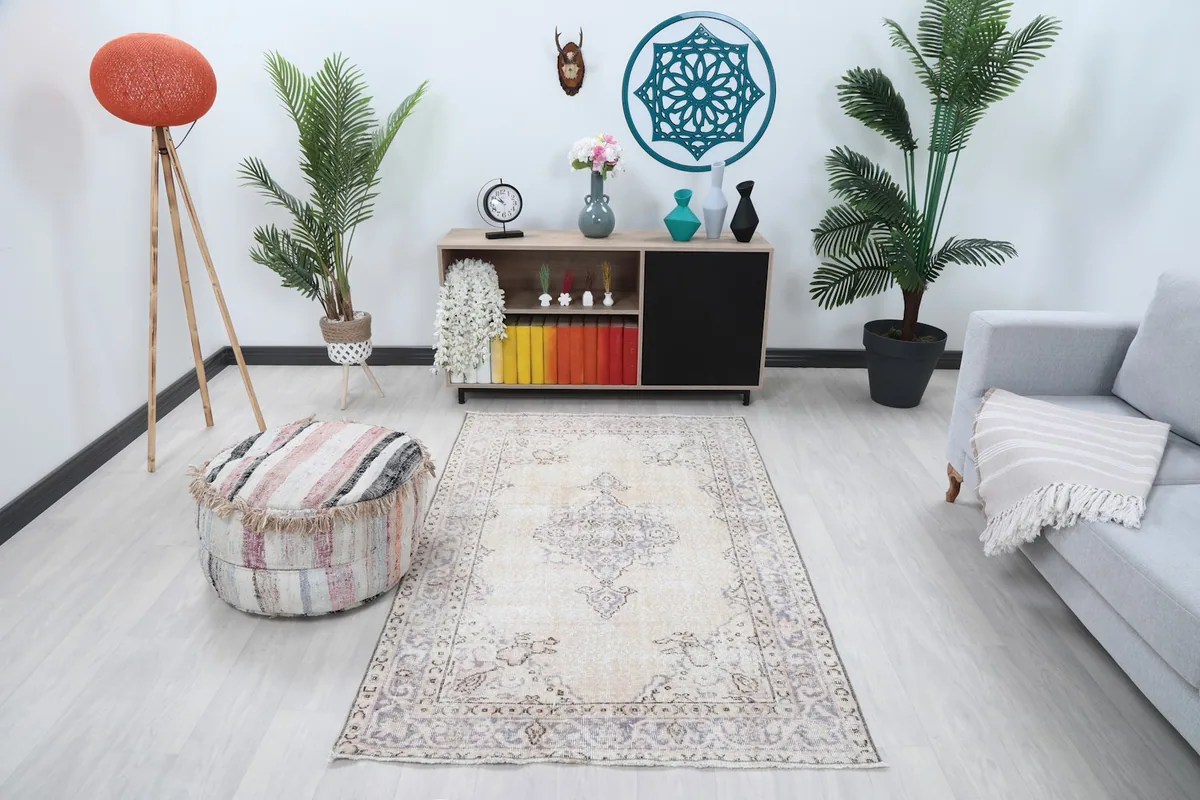 Vintage ivory and purple rug in a bright living room setup with a gray sofa and wooden cabinet