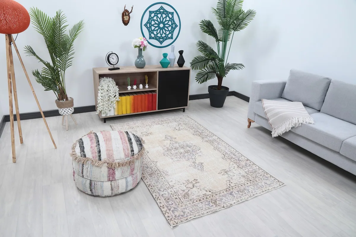 Overhead view of the ivory and purple rug in a modern living space with a striped ottoman